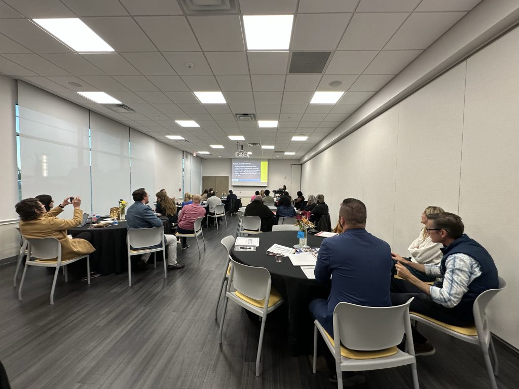 people sitting in conference room with PowerPoint presentation; Thriving Together Collaborative