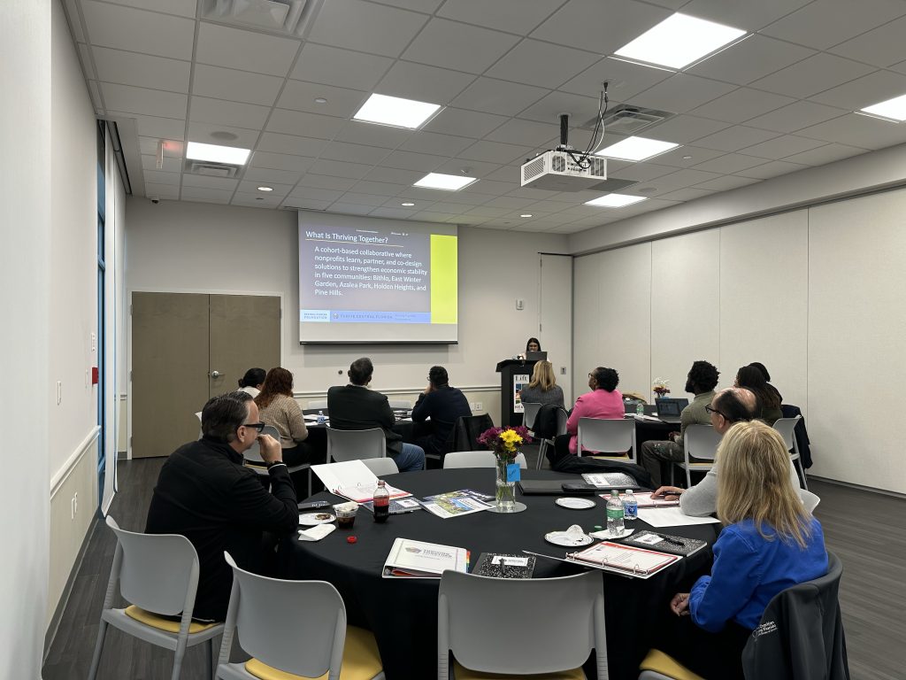 people sitting in a conference room with a PowerPoint presentation.